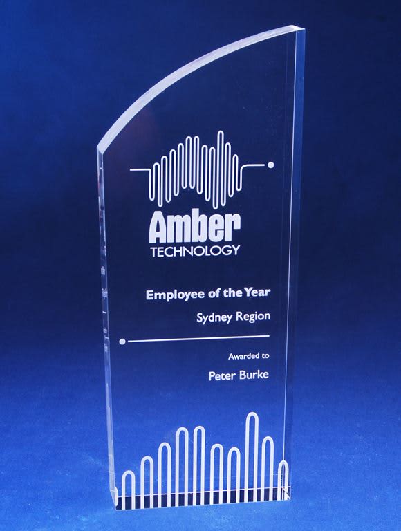 A clear acrylic trophy with a curved top, featuring engraved text and a logo. The base is flat and rectangular. Contemporary Acrylic Trophy with Laser Engraving - Image 1