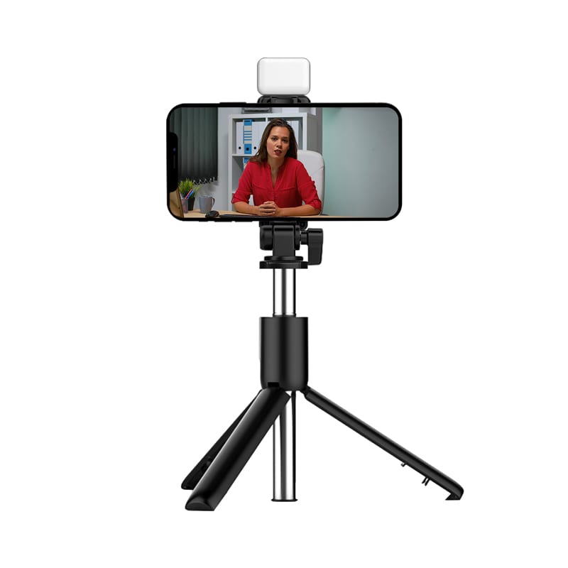 A black LED selfie stand with a tripod base, holding a smartphone displaying a video call. Reunion LED Selfie Stand - Image 1