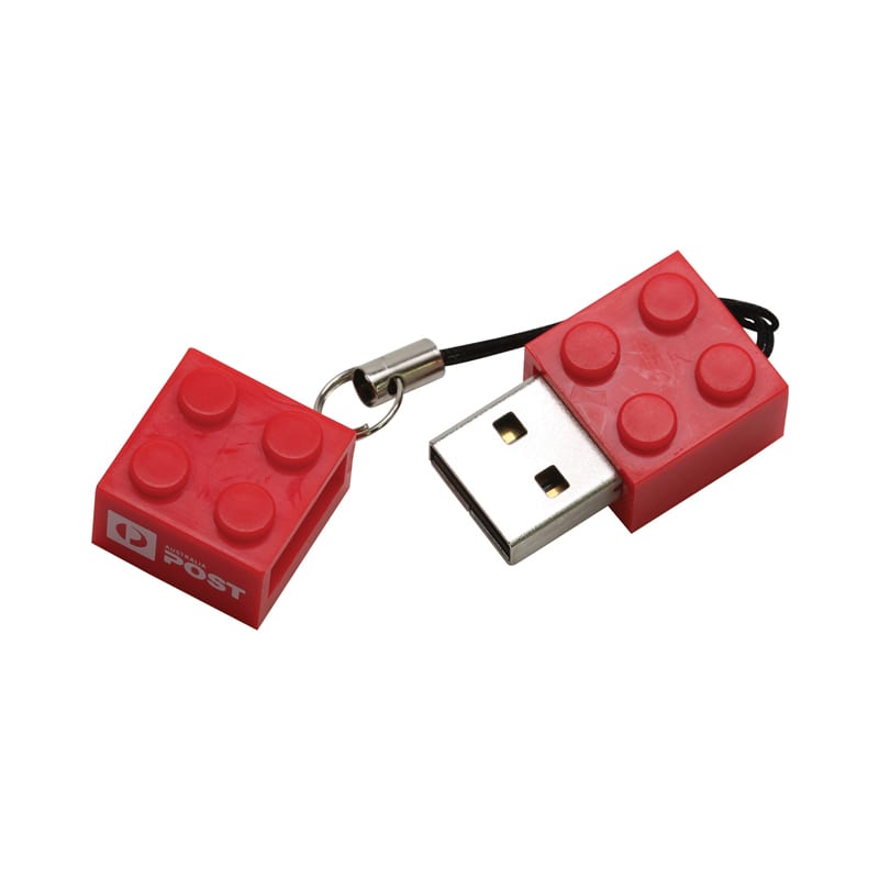 A red building block-shaped flash drive with a keychain attachment, featuring a logo. Building Block Flash Drive - Image 1