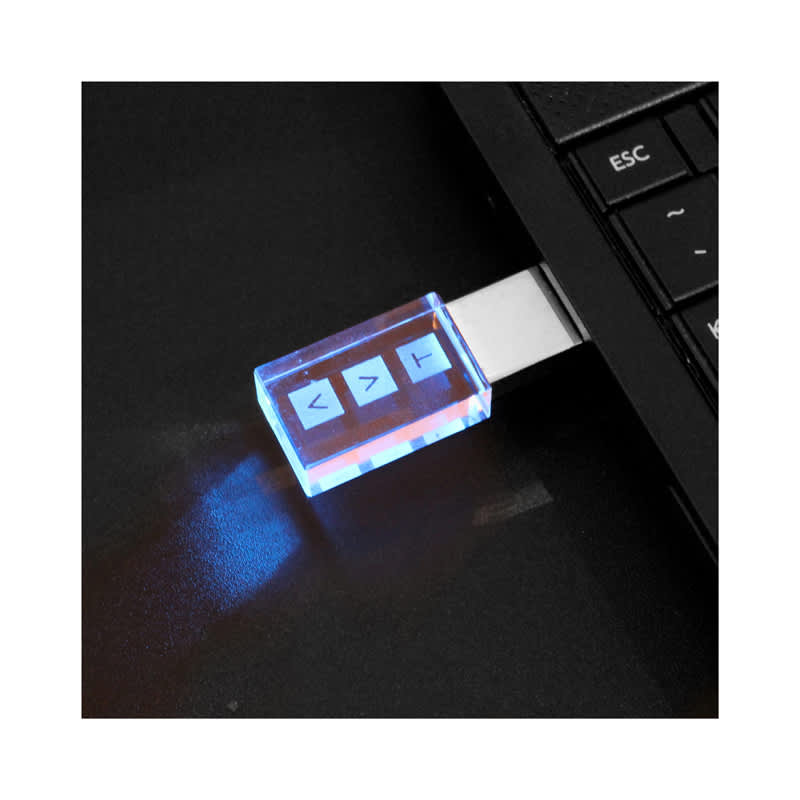 A 3D crystal flash drive with a transparent blue casing, plugged into a laptop's USB port, emitting a soft glow. 3D Crystal Flash Drive - Image 1