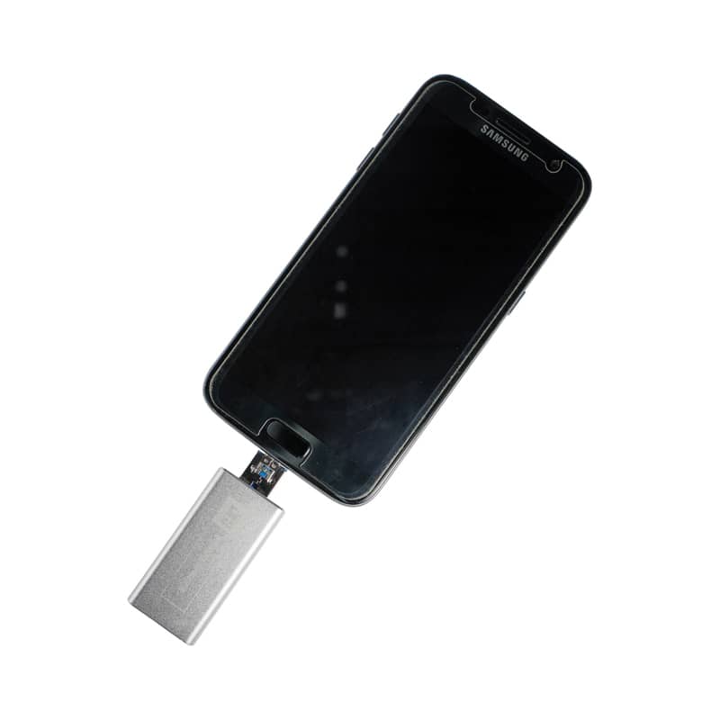 A silver Banion OTG USB 3.0 flash drive connected to a black smartphone. The device has a logo on it. Banion OTG USB 3.0 - Image 1