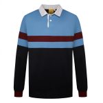 A sports jumper in blue, maroon, and black, featuring a collared neckline and long sleeves. It has a logo.