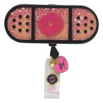 A retractable badge holder featuring a pink glitter design with a kiss motif and decorative charms in black and pink.