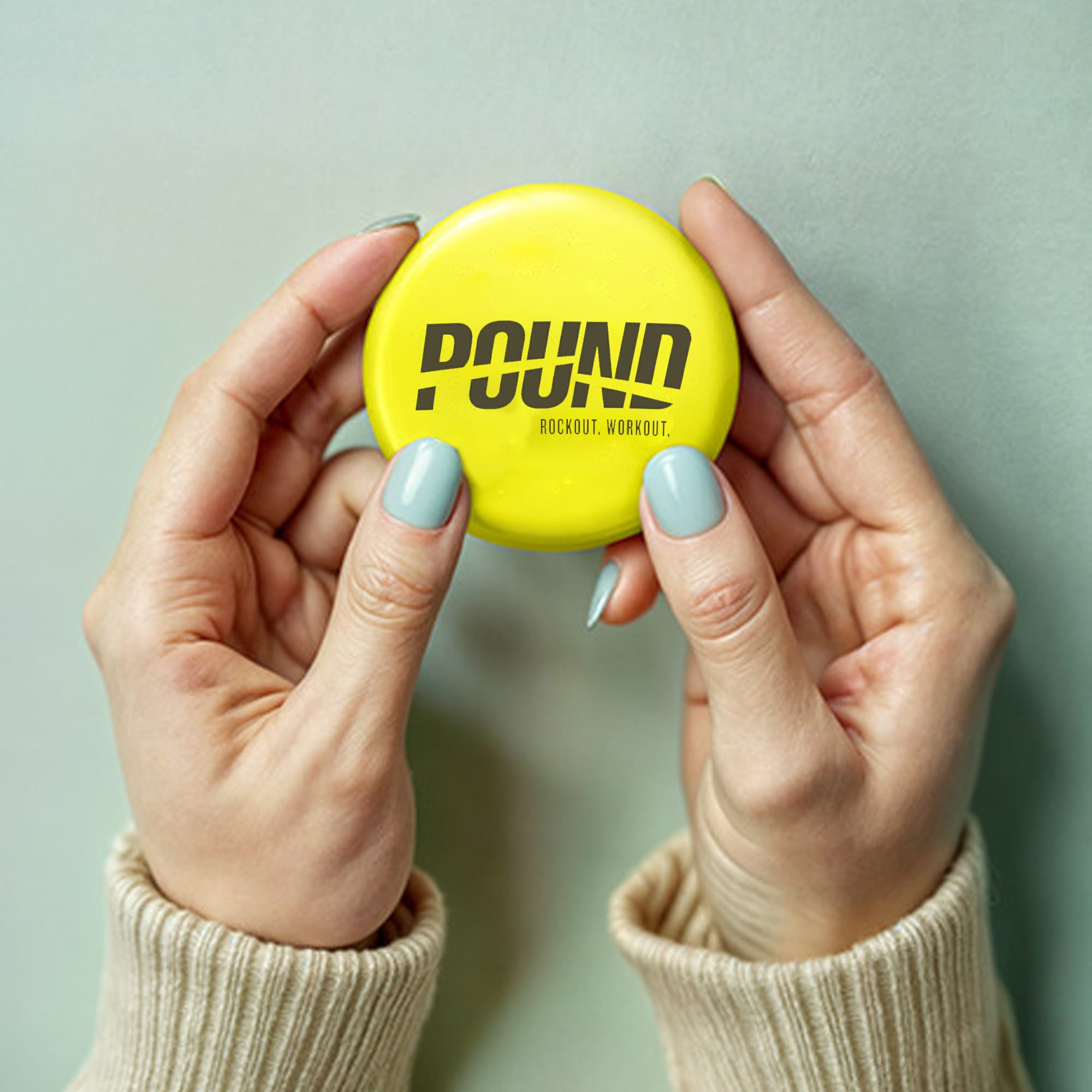 A round 75mm button badge in bright yellow, held between two hands, featuring a logo. Button Badge Round 75mm - Image 1