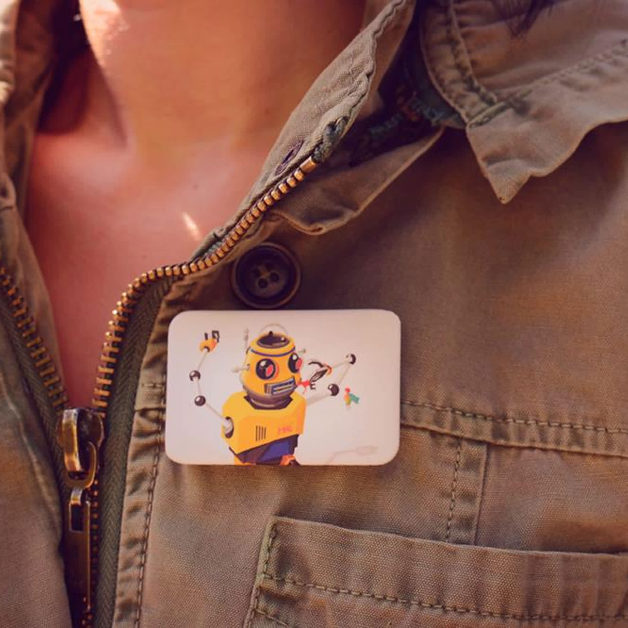 A rectangular button badge featuring a colourful robot illustration, pinned to a person’s jacket. Button Badge Rectangle - Image 1