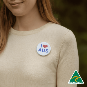 A 56mm button badge featuring a white background with blue text and a heart design, worn on a person's clothing.