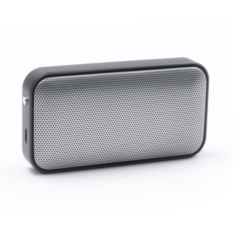 A compact black and silver wireless speaker with a mesh front design and a side port. It features a logo on the surface. Nano Vegan Wireless Speaker - Image 1