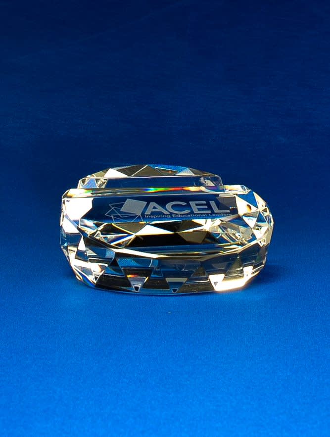 A crystal business card holder with a faceted design, featuring a logo, set against a blue background. Crystal Business Card Holder - Image 1