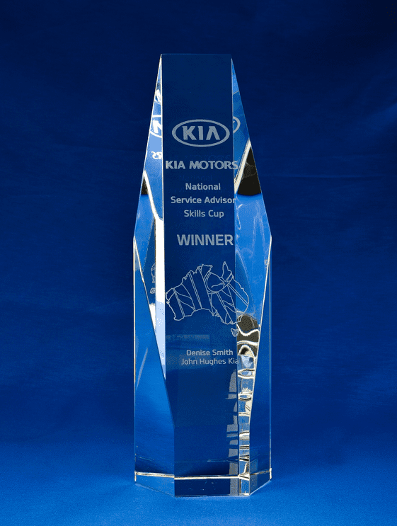A large, clear crystal trophy in a hexagonal shape, featuring engraving and a logo. The background is blue. Sliced Crystal Hexagon - Large + Gift Box - Image 1