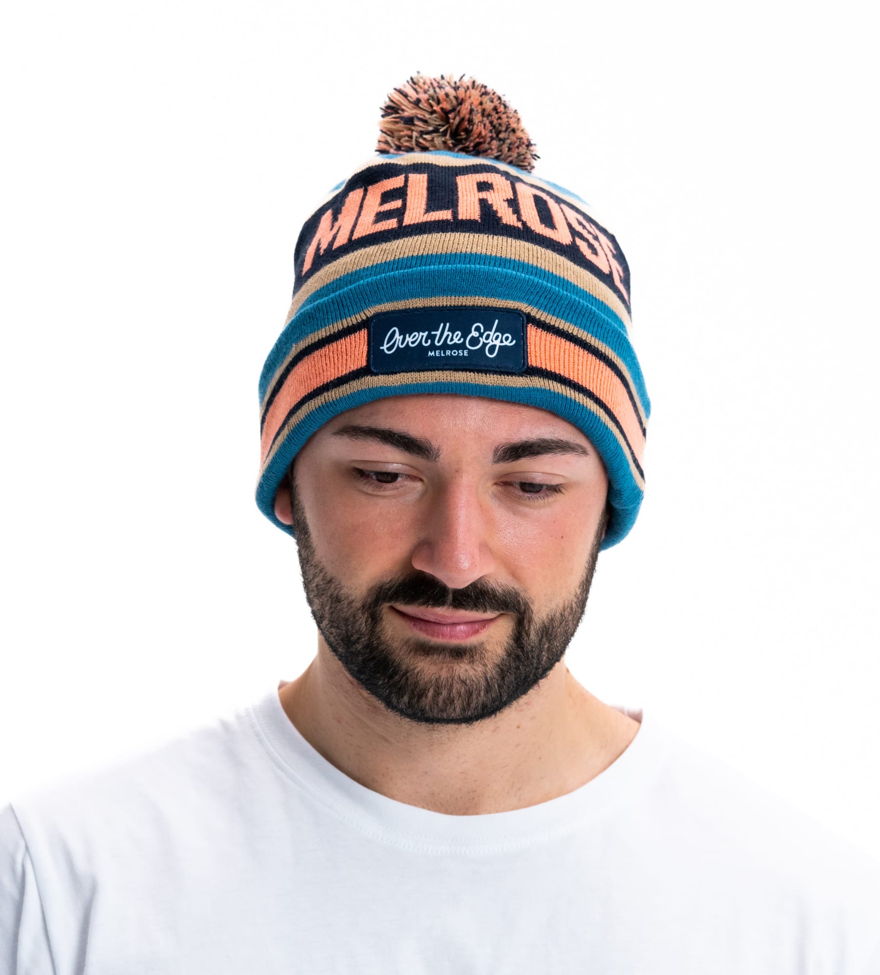 A blue and orange striped beanie with a pom pom on top, featuring a logo on the front. Custom Pom Pom Beanies - Image 1