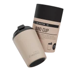 A reusable cup in beige with a black lid, featuring a branded design, packaged in a matching box.