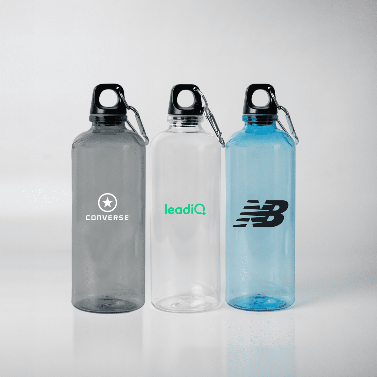 A drink bottle trio featuring grey, clear, and blue options, each with a carabiner and logos. Ember 700ml Plastic Bottle with Carabiner - Image 1