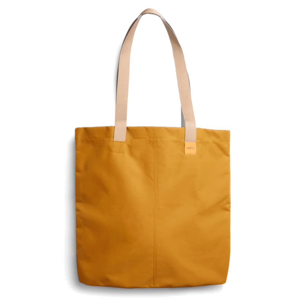 A mustard yellow tote bag with tan straps and a simple design. It features a logo on the front. Bellroy City Tote - Image 1