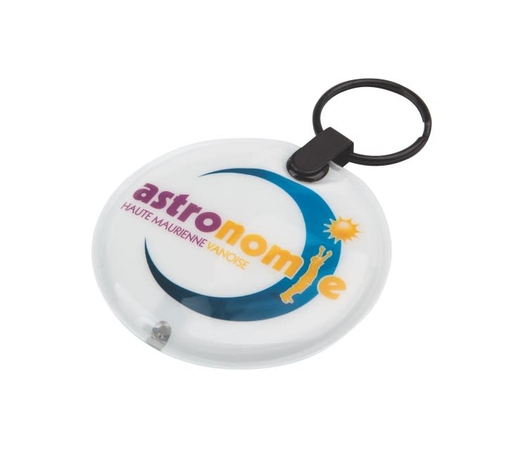 A circular white keyring with a black keychain attachment, featuring a logo that includes blue and yellow elements. Press-Light Keyring - Indent - Image 1