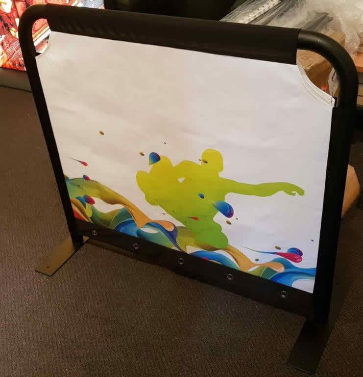 A café barrier featuring a vibrant illustration with green and blue designs, set in a sturdy black frame. A café barrier featuring a vibrant illustration with green and blue designs, set in a sturdy black frame.