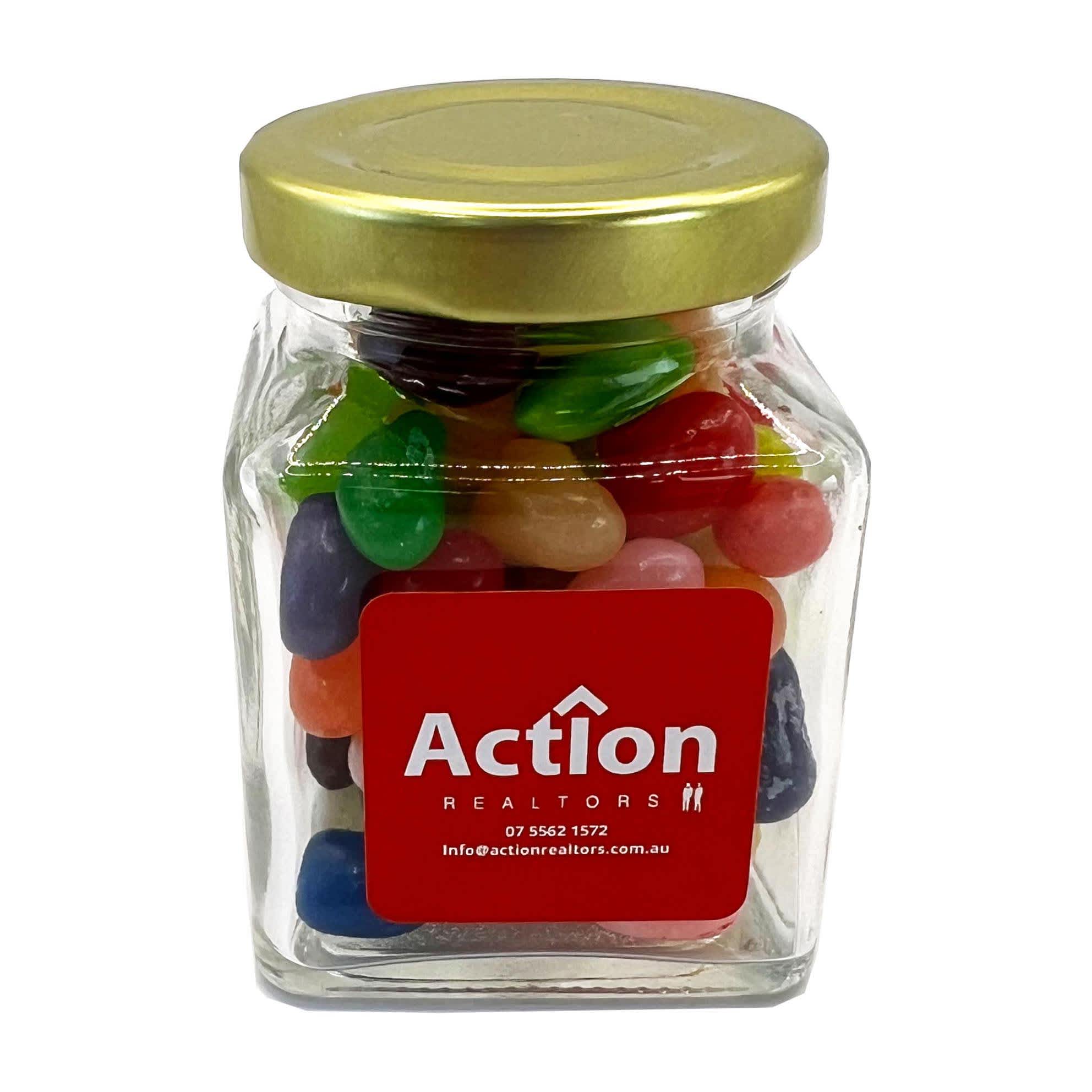 A small glass jar filled with colourful jelly beans, topped with a gold lid. The jar features a logo on the front. A small glass jar filled with colourful jelly beans, topped with a gold lid. The jar features a logo on the front.