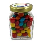 A small glass jar filled with chewy fruit candies in red, blue, green, yellow, and orange, capped with a gold lid.