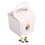 A coloured noodle box containing M&Ms in various colours, placed alongside colourful chocolate beans.