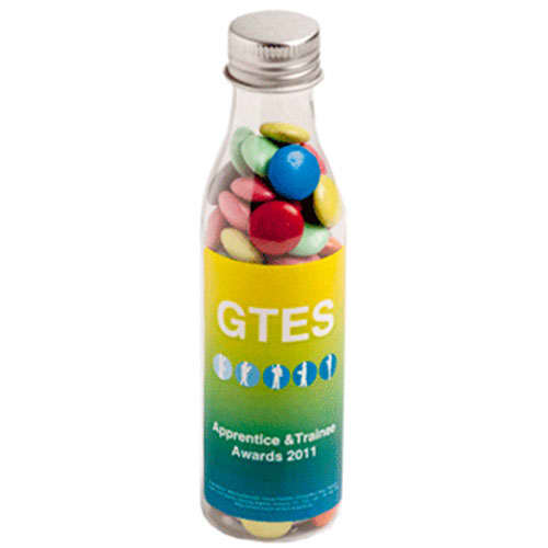 A drink bottle filled with multi-coloured choc beans, featuring a logo and a gradient yellow-green design. Soda Bottle with Choc Beans 100g - Image 1