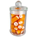 A glass apothecary jar filled with orange rock candy pieces, featuring a clear lid.