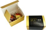 A gold and white box containing two chocolate balls, featuring branding on the exterior.
