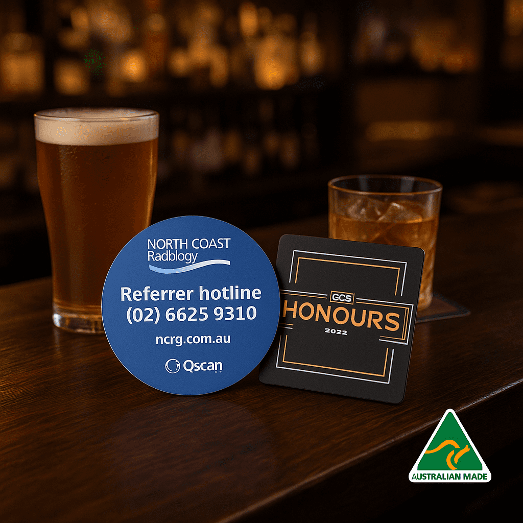 A drink bottle and two circular coasters in blue and black, featuring logos and text, on a wooden bar top. Deluxe Coaster (1mm) - Image 1