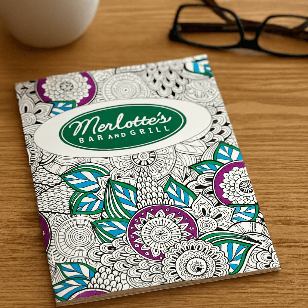 A5 colouring book featuring intricate floral designs in purple, blue, and green, with a logo on the cover. A5 Colouring Books - Image 1