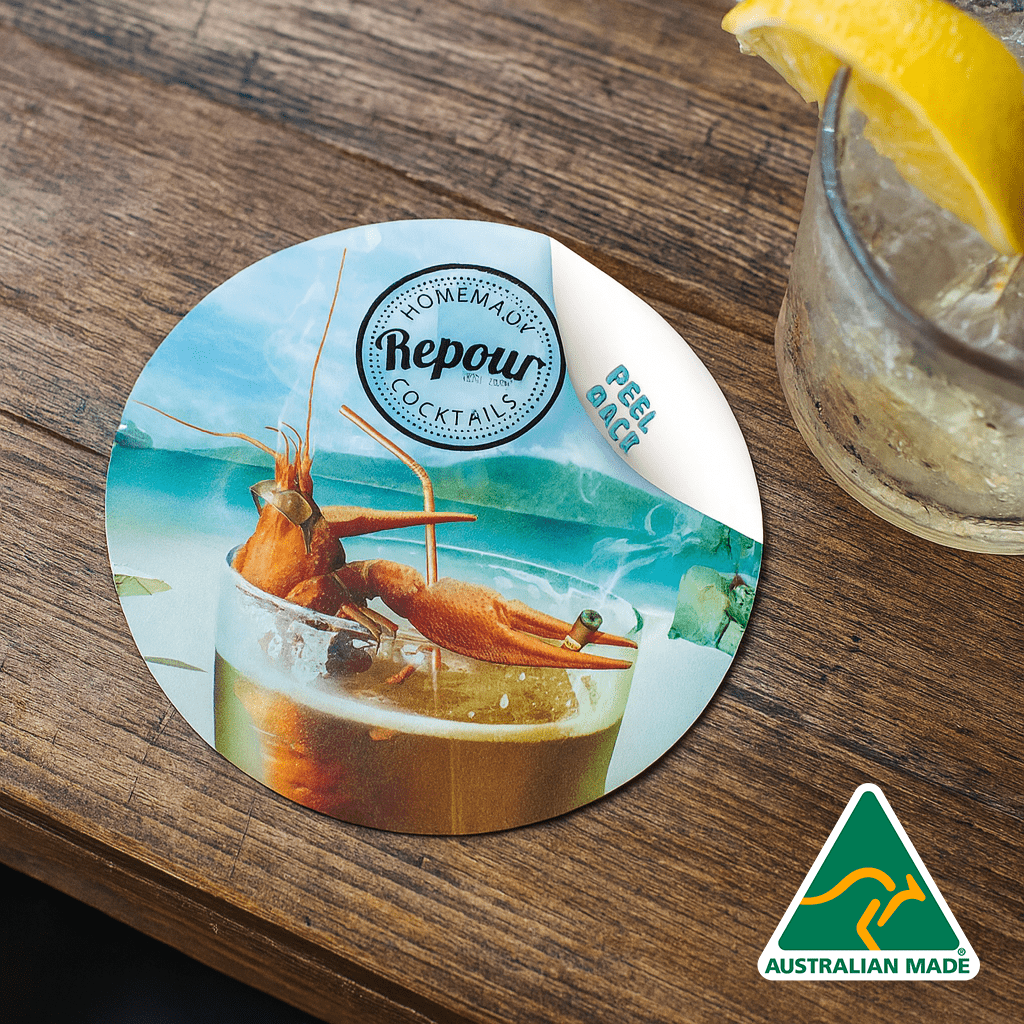 A round, colourful coaster featuring a cocktail and seafood, with an Australian made logo in one corner. Ezi Gripz Coasters (95mm x 95mm) - Image 1