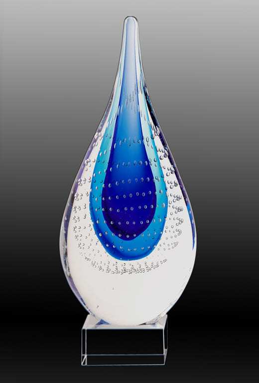 A light blue and blue art glass trophy featuring a teardrop design with bubble patterns, mounted on a clear base. Art Glass Trophy - Dante Sculpture Light Blue/Blue with Printed Plate - Image 1
