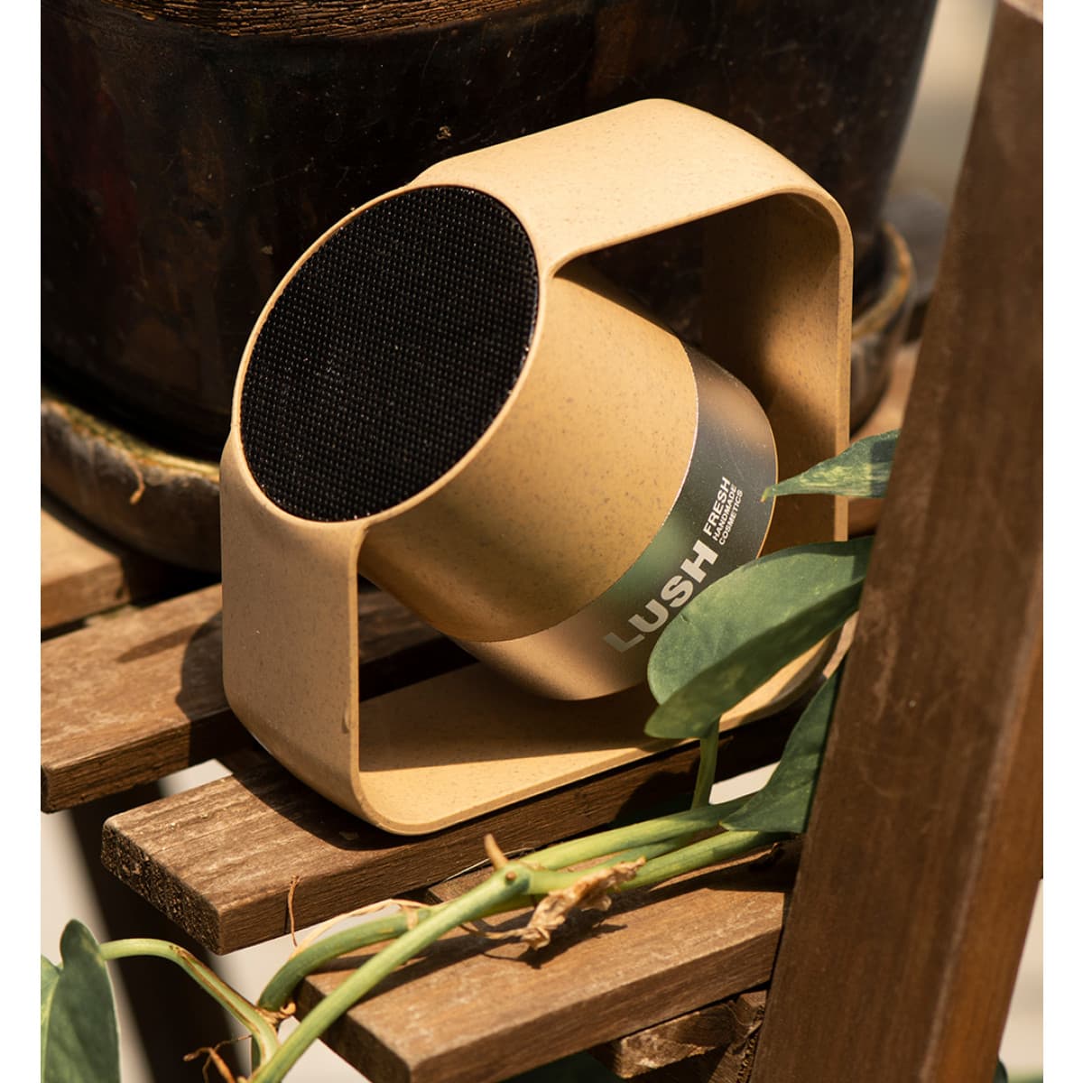 A wireless speaker in a circular design featuring a beige casing and a black speaker grille, set on a wooden surface. Kobra Wireless Speaker - Image 1