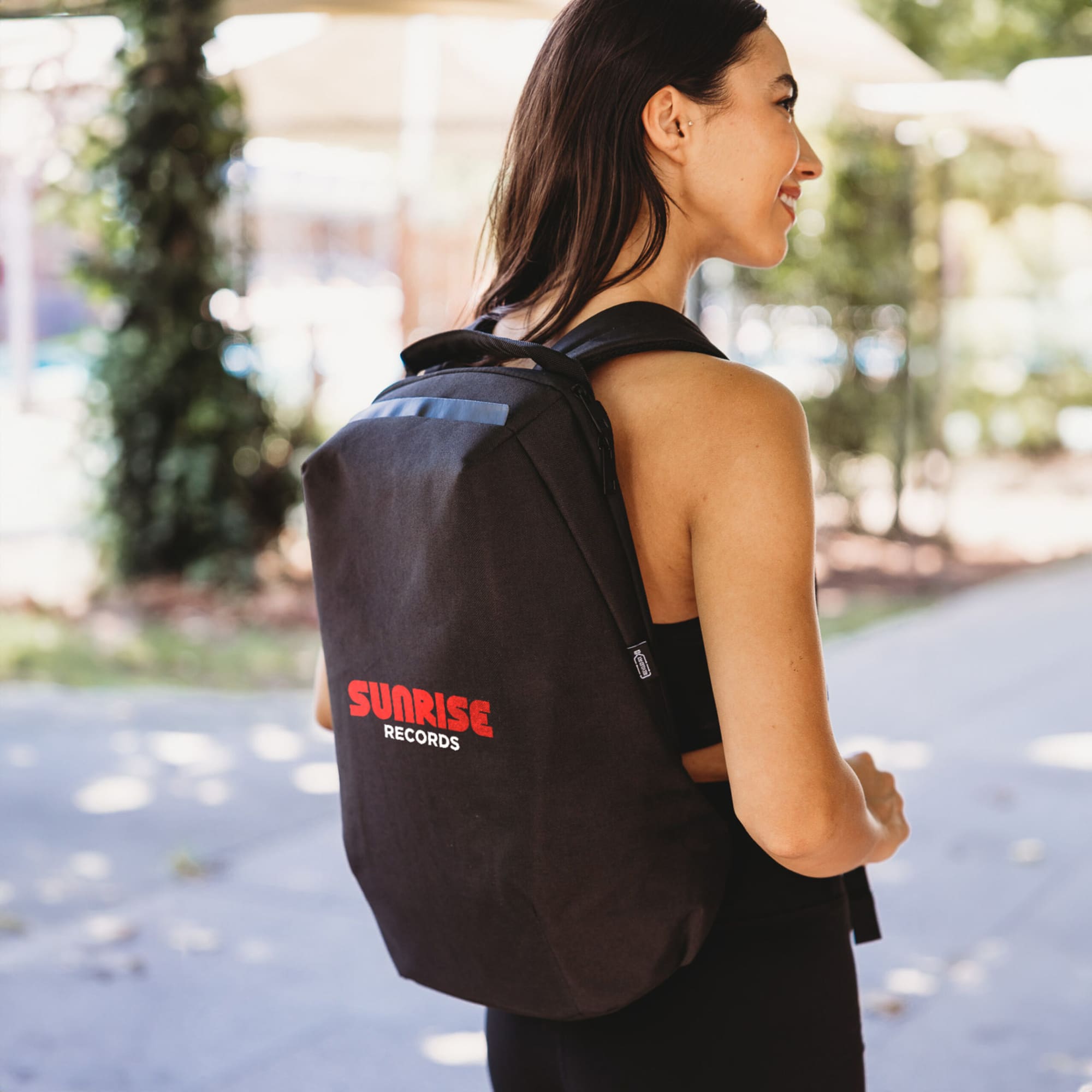 A black backpack with a logo, worn by a woman outdoors. The design is sleek and modern. ECO NOVA Computer Backpack - Image 1