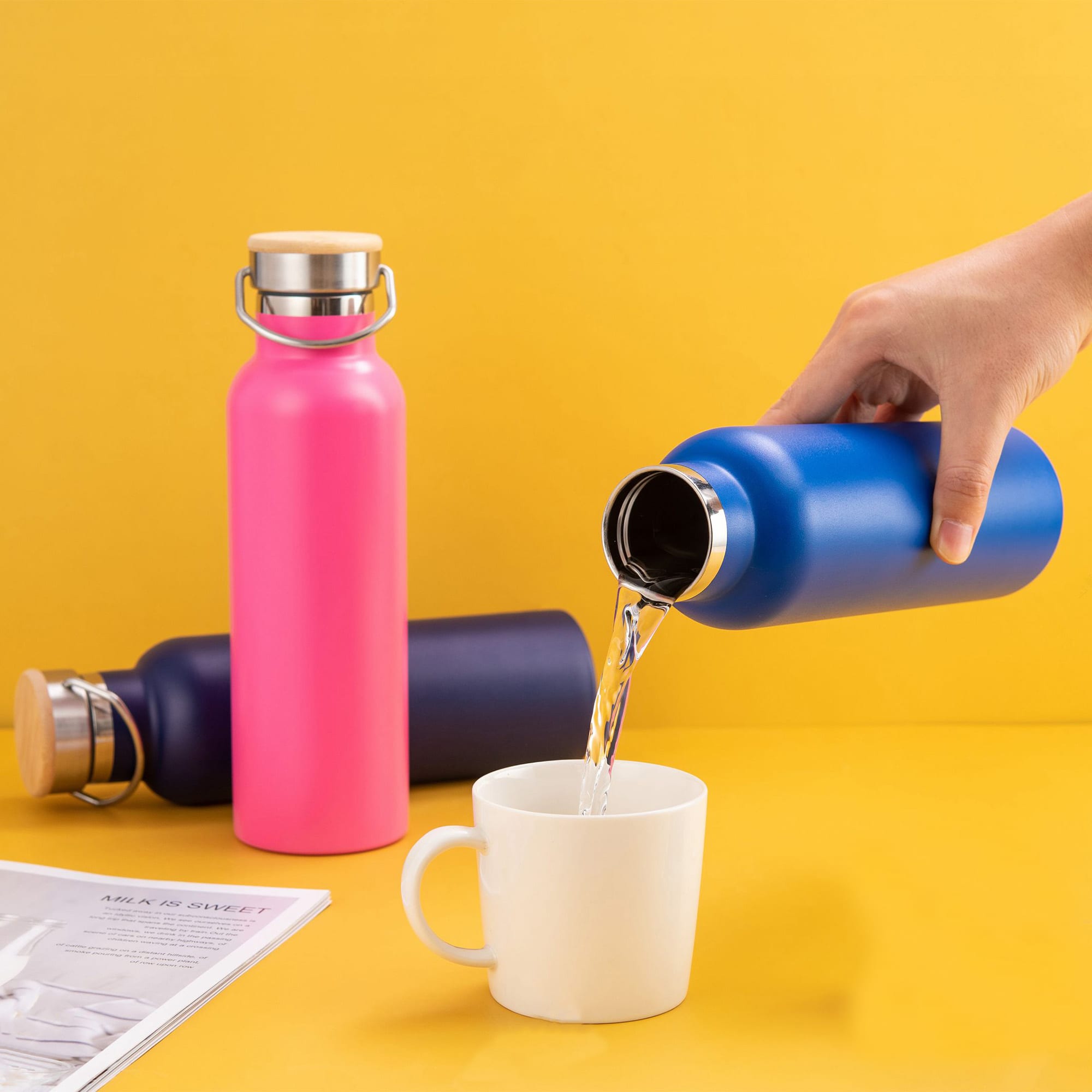 A drink bottle in vibrant pink and blue, with a stainless steel lid, is being poured into a white mug. Miami Drink Bottle - Image 1