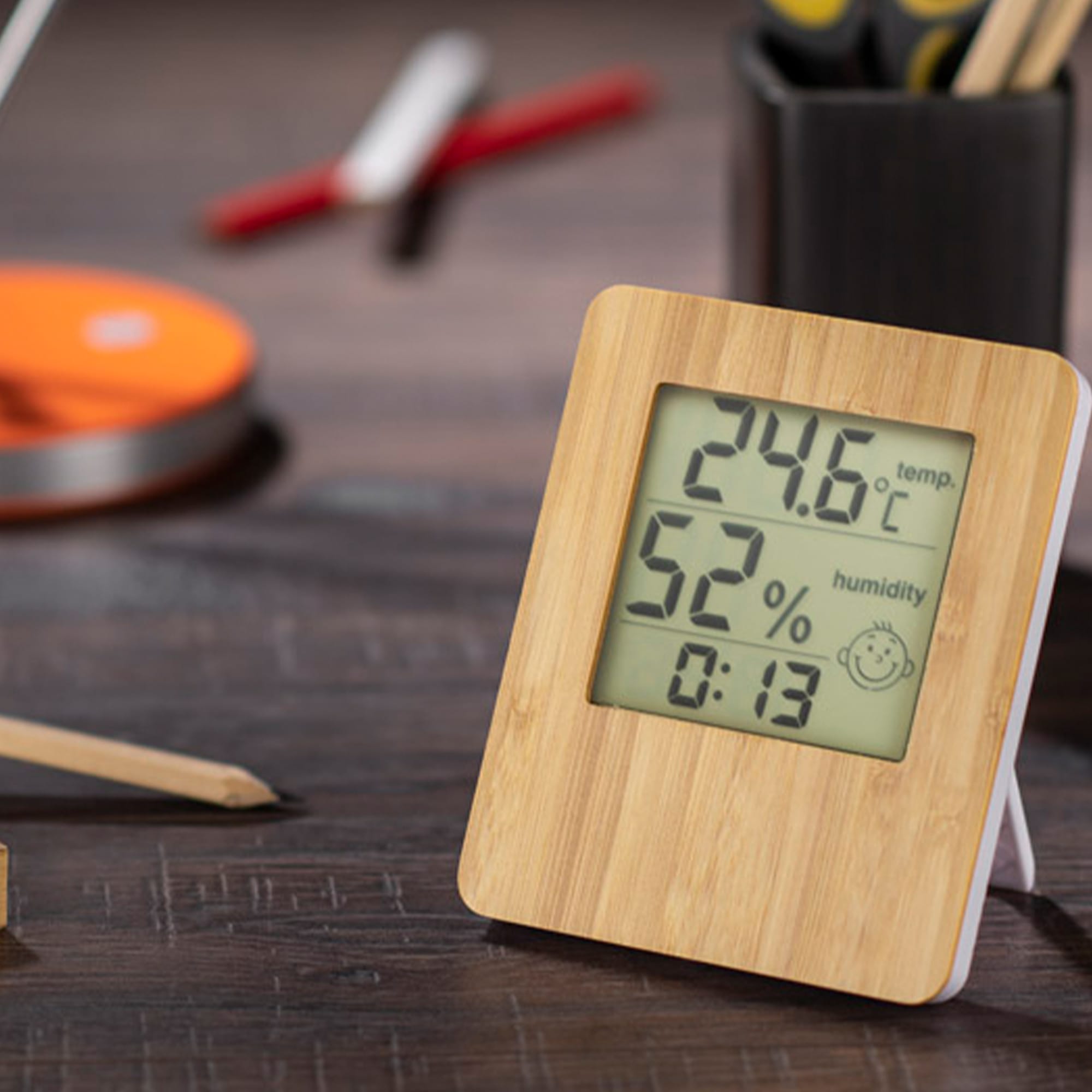 A bamboo desk clock with a digital display showing temperature, humidity, and time, set on a wooden surface. Bamboo Desk Clock - Image 1