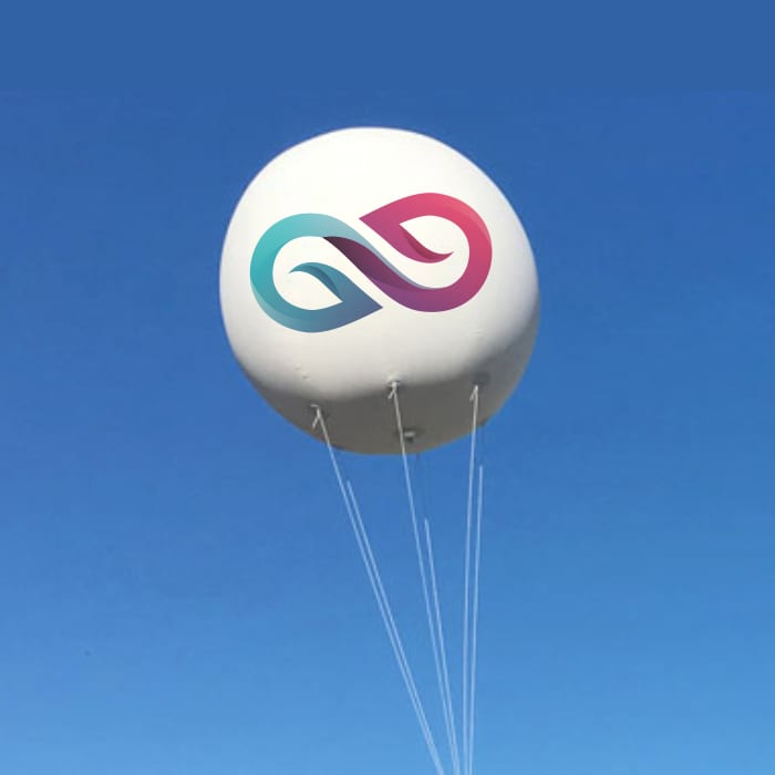 An inflatable advertising balloon in white, featuring a logo with teal and pink elements, floating against a blue sky. Inflatable Advertising Balloon - Image 1