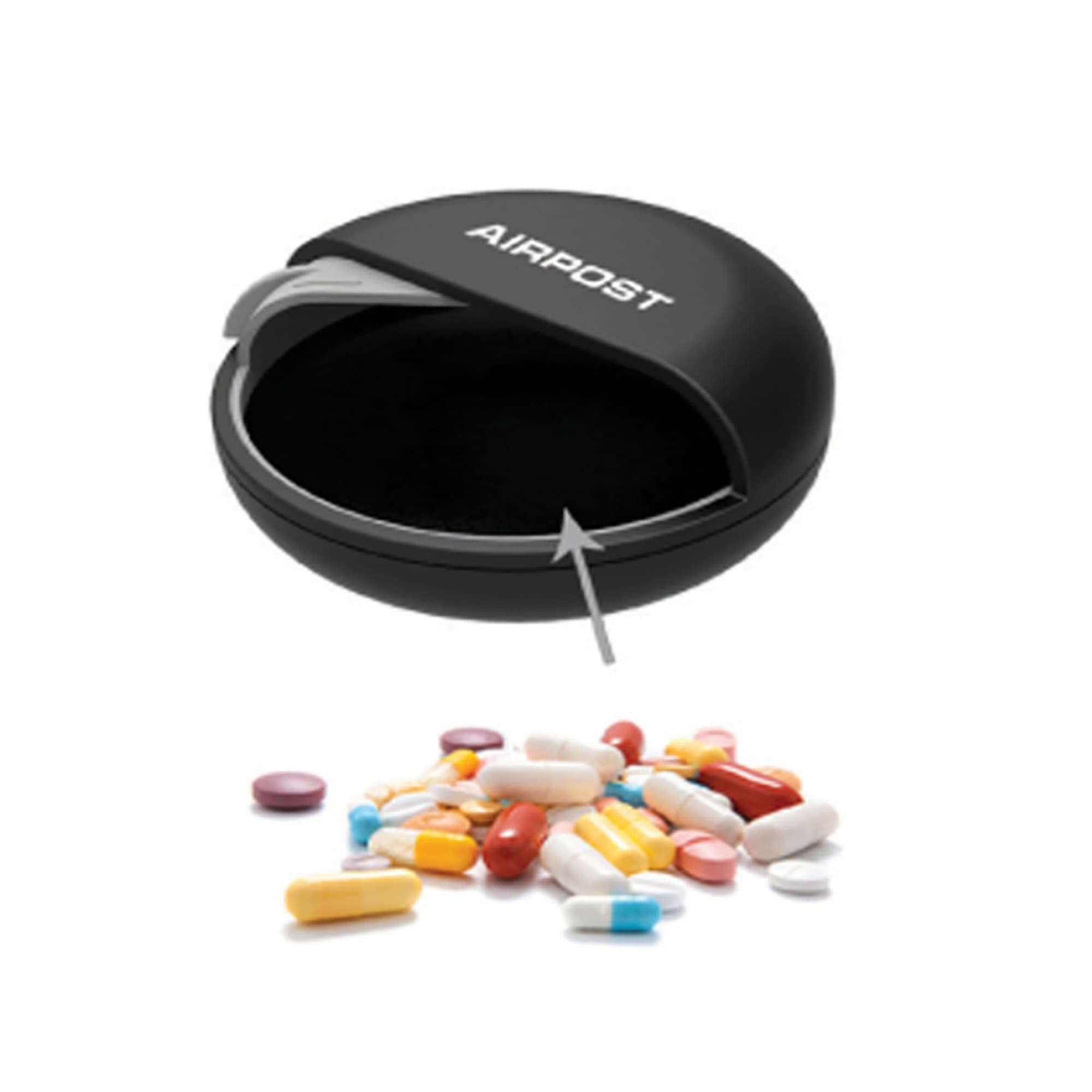 A black pill box with a hinged lid, surrounded by a variety of colourful pills. The box features a logo. Pill Box - Image 1