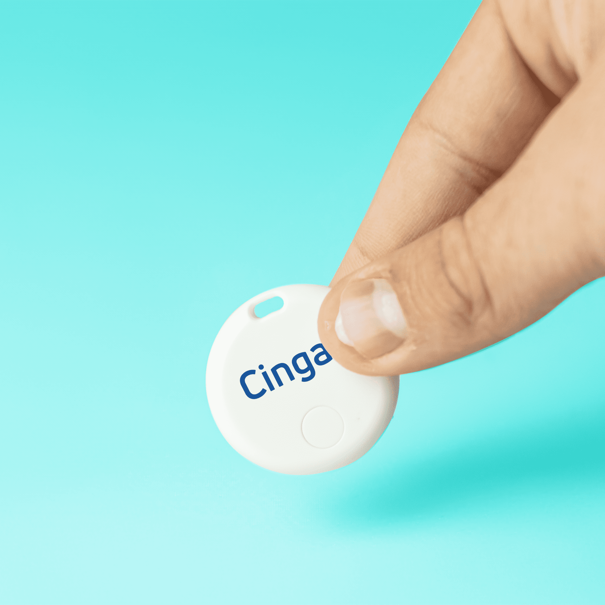 A white circular item tracker held between two fingers, with a blue logo and a smooth surface against a turquoise background. SeekTag Dual System Item Tracker - Image 1