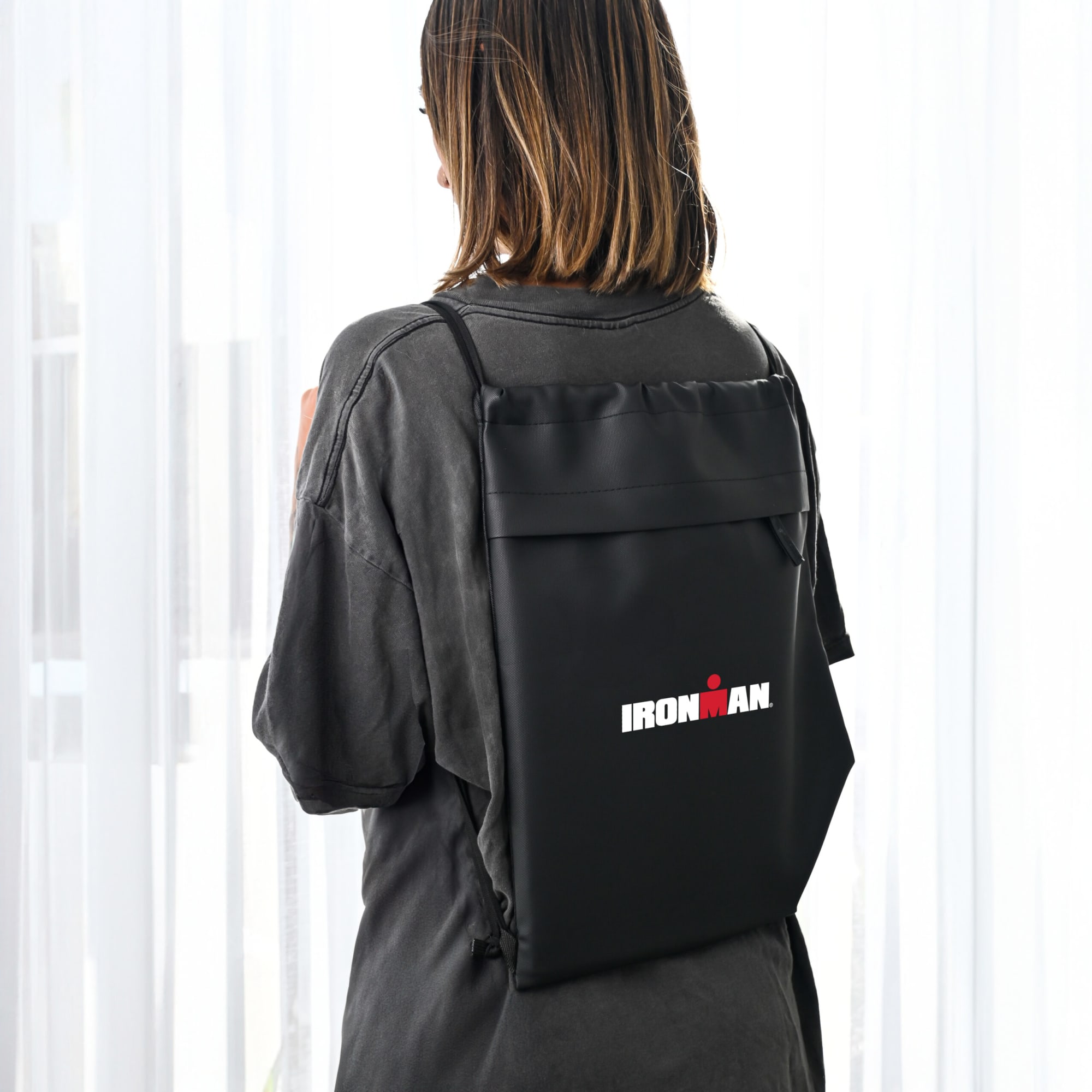 A black drawstring bag with a logo, worn on the back of a person, featuring a sleek design. The SWAG RPET Drawstring Bag - Image 1