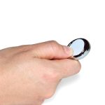A hand holds a shiny, silver ball marker designed for use in golf.