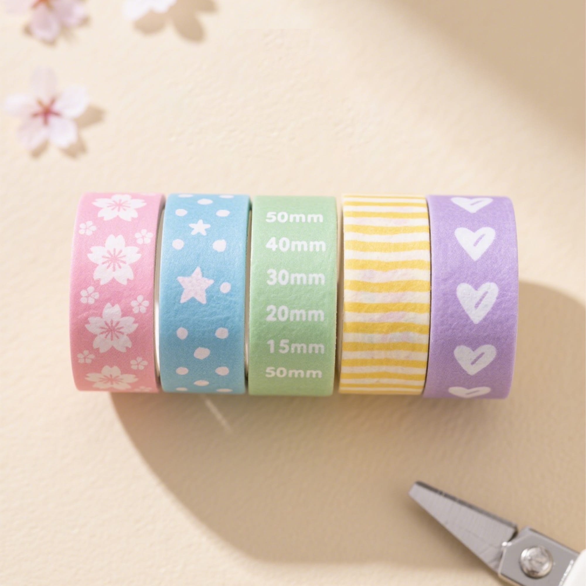 Five rolls of washi tape in pastel colours: pink with flowers, blue with stars, green, yellow striped, and purple with hearts. Washi Tape - Image 1