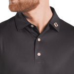 A men's black polo shirt featuring a tonal dot print, with a logo on the collar and three buttons.