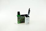 A two-compartment pen pot in black and white, holding a black pen, a green marker, and a paperclip. It features a logo.