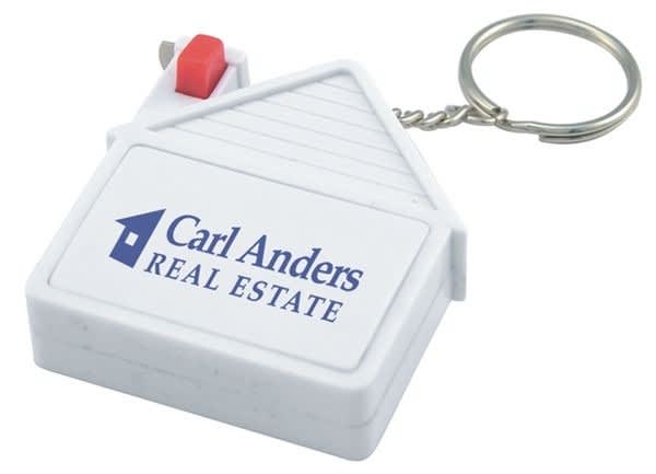 A house-shaped tape measure in white with a keyring attachment and a red button, featuring a logo. House Tape Measure - Image 1