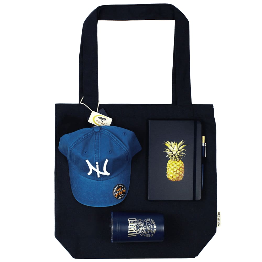 A navy tote bag holds a blue cap, a pineapple notebook, a pen, and a drink bottle, all featuring a logo. Lifestyle Essentials Pack - Image 1