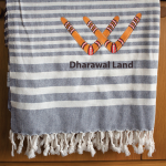 A blue and white striped throw blanket with a fringed edge and a logo featuring boomerangs and the text "Dharawal Land."