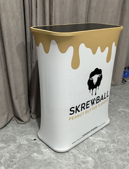 A stretch fabric light box counter in white and gold, featuring a logo and a smooth, rounded design. Stretch Fabric Light Box Hydraulic Counter - Image 1