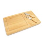 A bamboo cheese board with a carving section and two stainless steel cheese knives featuring wooden handles.