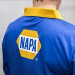 A men's long sleeve fishing polo in blue with a yellow collar and a logo on the back.