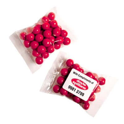 A transparent bag containing round, orange chocolate drops, resembling Jaffa lollies. Orange Choc Drops (Jaffa look alike) 100g - Image 1