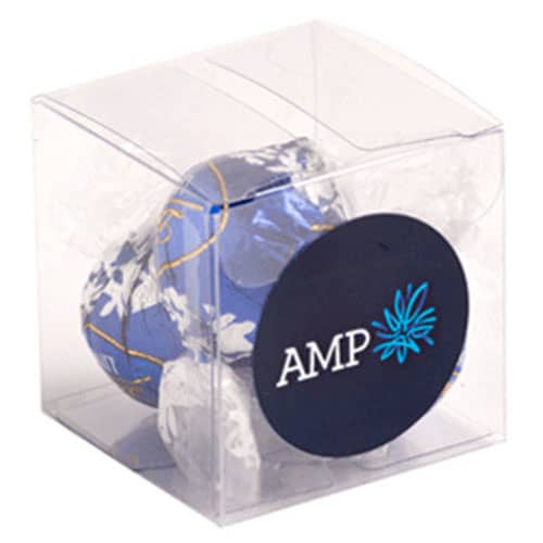 A clear cube packaging containing blue and white wrapped chocolate balls. The packaging features a logo. A clear cube packaging containing blue and white wrapped chocolate balls. The packaging features a logo.