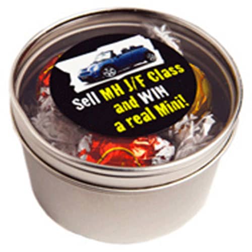A silver round tin filled with colorful Lindt chocolate balls. The tin has a label with a logo. Small Round Window Tin with Lindt Balls - Image 1